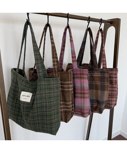 Detailed close-up of multi-color plaid fabric tote bags displayed on a wooden wall rack