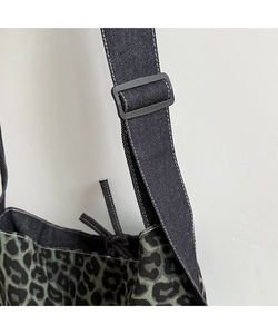 Close-up of adjustable fabric shoulder strap with buckle on leopard print tote bag