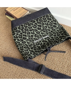 Detail of leopard print shoulder bag with Bonne journée text on woven mat background