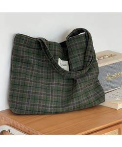 Close-up of retro plaid tote bag in dark green wool fabric on a wooden table