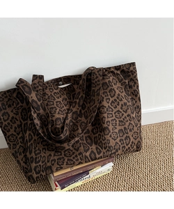 Detailed shot of leopard print canvas tote bag on textured rug with vintage books