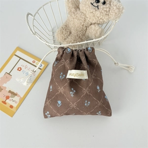 Detailed view of a brown corduroy drawstring pouch with blue floral print and logo label