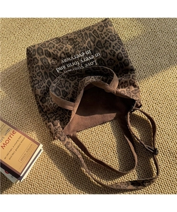 Vista detallada del bolso tote de leopardo con texto blanco sobre un fondo cálido