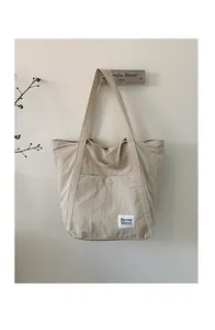 Close-up of beige nylon tote bag featuring minimalist Beyou Merci logo label and texture