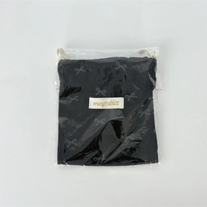 Detail of black corduroy drawstring pouch with bow print in plastic packaging
