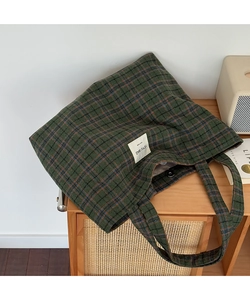 Close-up of green checkered tote bag with woven label and magnetic snap closure