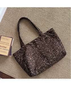 Detailed view of the leopard print canvas tote bag texture on a beige woven mat background