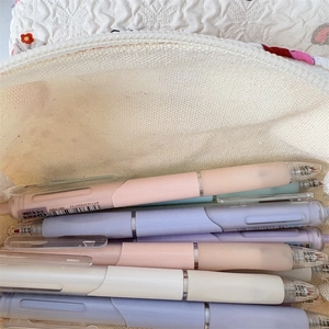 Gros plan de stylos gel pastel dans une trousse à crayons blanche matelassée