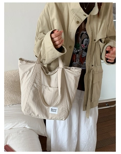 Detail of minimalist beige canvas tote bag with front pocket and branded woven label
