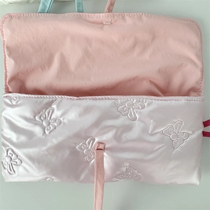 Detail of pink quilted bow satin pencil case showing soft fabric texture and flap opening