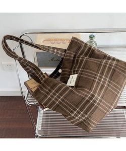 Detail of checkered tote bag fabric with magnetic closure on a metal shelf