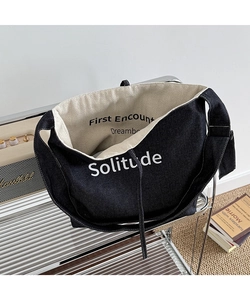 Detail of black canvas tote bag showing interior lining and Solitude print texture