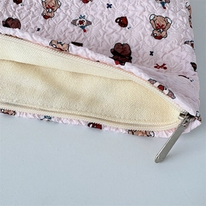 Gros plan d'une trousse à maquillage rose gaufrée avec texture matelassée et zip
