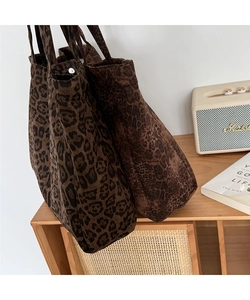 Detail of leopard print canvas tote bags with metallic snap buttons on a wooden rack