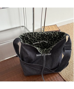Detail view of denim tote bag featuring leopard print lining and French slogan text