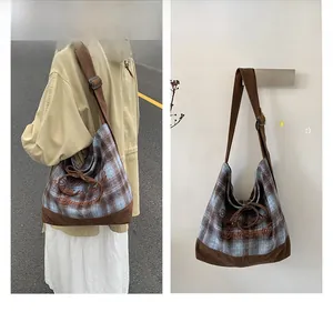 Close-up of plaid canvas shoulder bag featuring corduroy patchwork and vintage embroidery