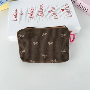 Détail d'une pochette en velours côtelé marron avec motifs de nœuds et fermeture éclair