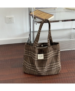 Detail of checkered tote bag with woven logo label and magnetic buckle closure