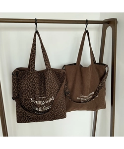 Detalle de bolsos tote en lona de leopardo y pana marrón con letras blancas de eslogan