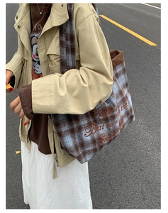 Close-up of brown and blue plaid tote bag with text embroidery and corduroy trim detail