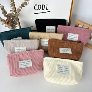 Detail view of multi-color corduroy cosmetic bags with ribbed texture and woven labels