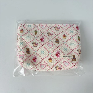 Détail de la trousse de maquillage matelassée blanche avec fleurs roses et motifs d'animaux