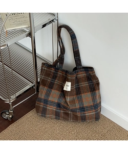 Detail of vintage plaid tote bag made of thick wool fabric with brand label on straw mat