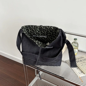 Large black denim tote bag with vibrant green leopard print lining and shoulder strap