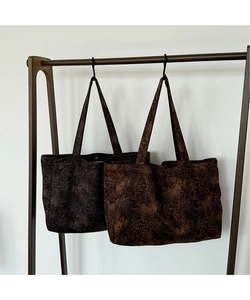 Detail of leopard print canvas tote bags in grey and brown hanging on a wooden rack
