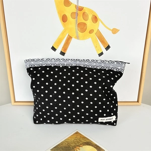 Detail of black polka dot corduroy cosmetic bag with white lace trim and zipper closure