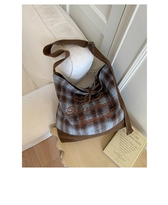 Detail of blue plaid and brown corduroy shoulder bag with elegant cursive embroidery