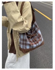 Detailed street shot of a plaid canvas tote bag with corduroy stitching and embroidery