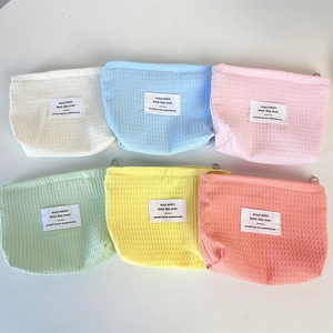 Flat lay of six colorful cotton waffle texture cosmetic bags with top zipper and woven label