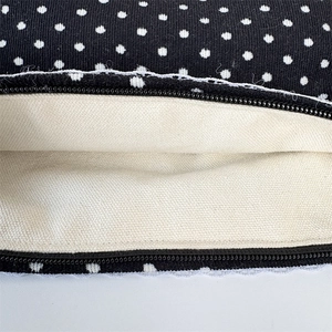 Detailed macro view of black polka dot corduroy bag with delicate white lace zipper trim