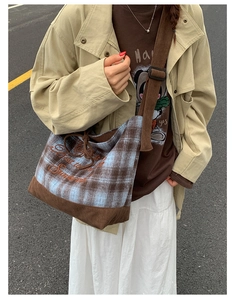Detailed view of plaid canvas shoulder bag with corduroy trim and cursive embroidery