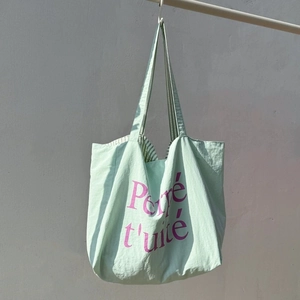 Détail du cabas en nylon vert menthe avec texte violet et doublure rayée élégante