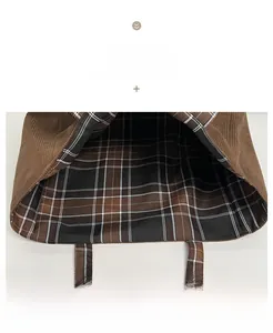 Detail of brown corduroy tote bag showing textured exterior and plaid pattern lining