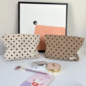 Detailed close-up of retro polka dot corduroy cosmetic bags with soft texture and brand label