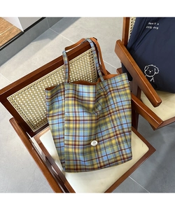 Détail du cabas en toile à carreaux bleu et jaune avec écusson rond et texture