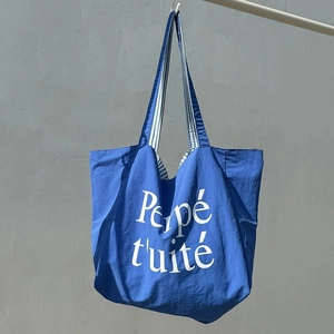 Détail du cabas en nylon bleu roi avec imprimé blanc Perpé tuité et doublure rayée