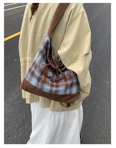 Detail view of plaid and corduroy shoulder bag with embroidery on casual female model