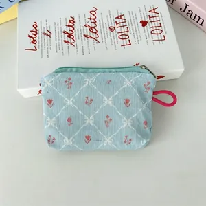 Détail de la pochette en velours bleu clair avec motif tulipes et cordon de serrage