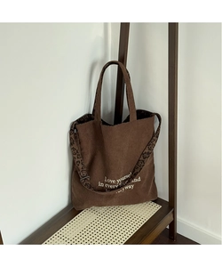 Detalle del bolso tote de pana marrón con correas de leopardo y estampado de letras blancas