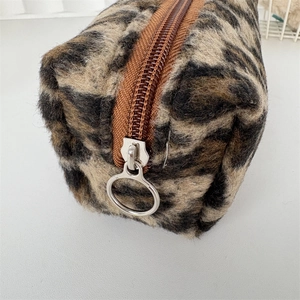 Close-up of leopard print plush pouch with a silver ring zipper and soft texture