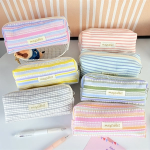 Detail view of colorful pleated stripe stationery pouches with brand logo and zipper
