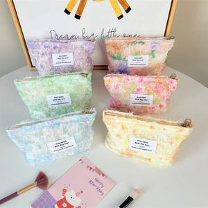 Multiple colorful plush makeup bags with floral patterns and zipper closure on a desk