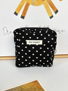 Close-up of black corduroy polka dot makeup bag with May Rabbit label and zipper