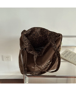 Detalle del bolso tote de pana marrón con asas de leopardo y cita impresa en color blanco