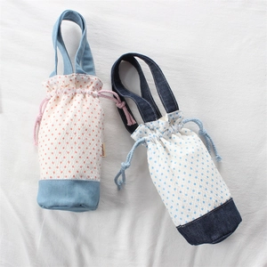 Dettaglio di borse per borracce in denim a pois con chiusura a coulisse e manico