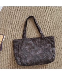Detailed top view of a dark leopard print canvas tote bag on a woven texture mat